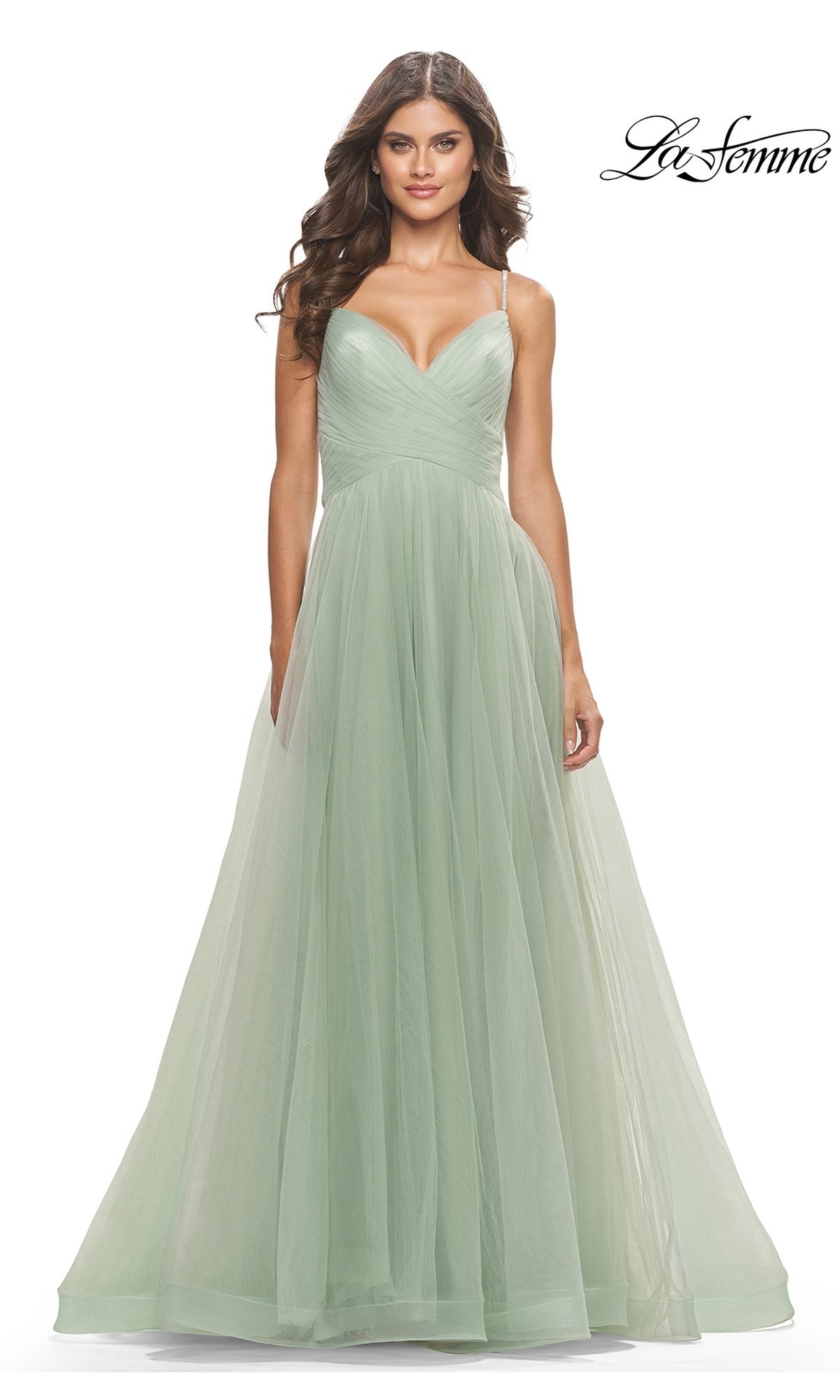 A woman stands against a white background wearing the La Femme A-Line Long Tulle Prom Dress 31204 in light green, featuring spaghetti straps, a fitted bodice, and a floor-length silhouette.